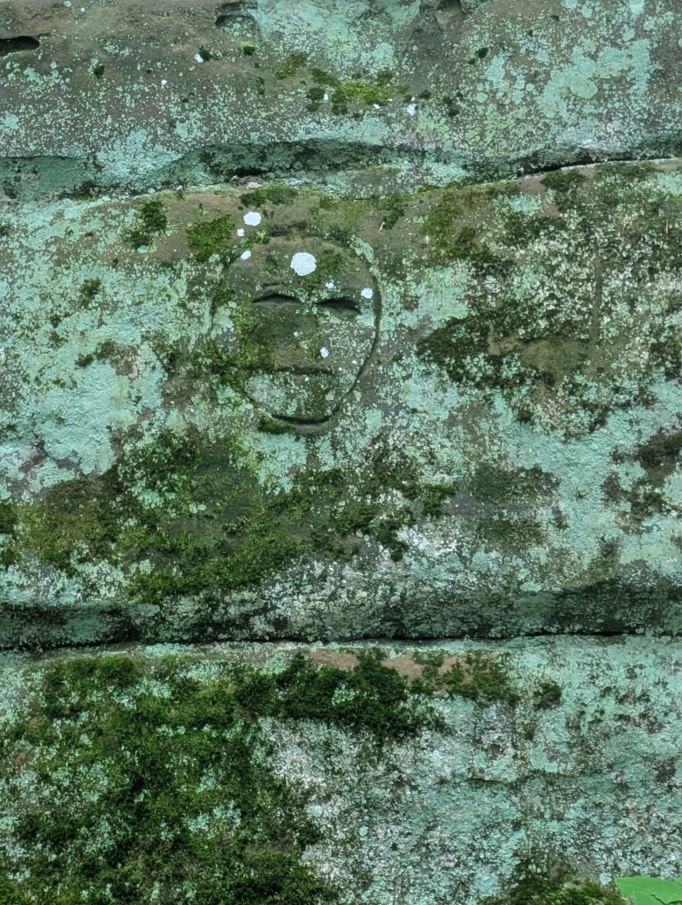 A small carved face, just a round face with big eyes and a straight line of a mouth