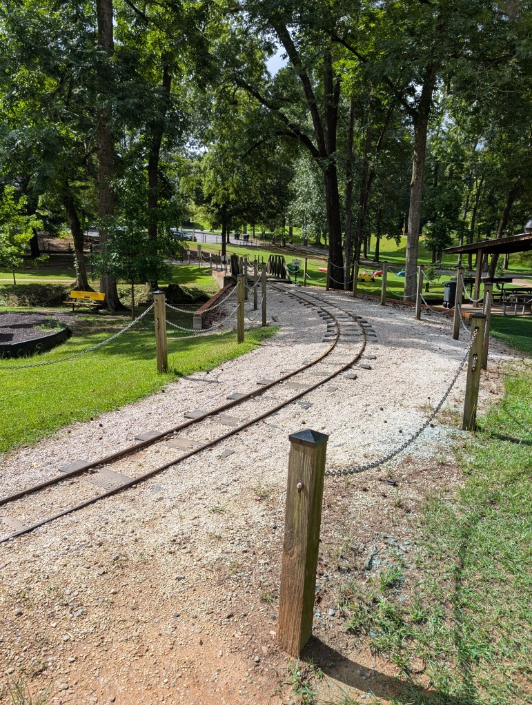 A small railroad track runs through a park.