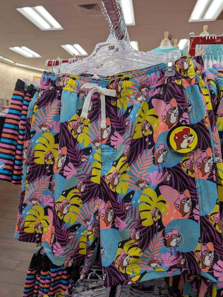 A very loud pair of swim trunks in tropical colors with the Bucc-ee head emblem all over them