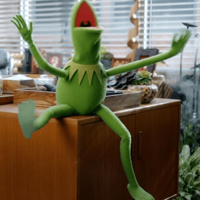 Kermit sitting on a desk flailing his arms like the icon he is